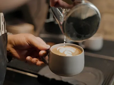 Barista fazendo latte art numa xícara de café