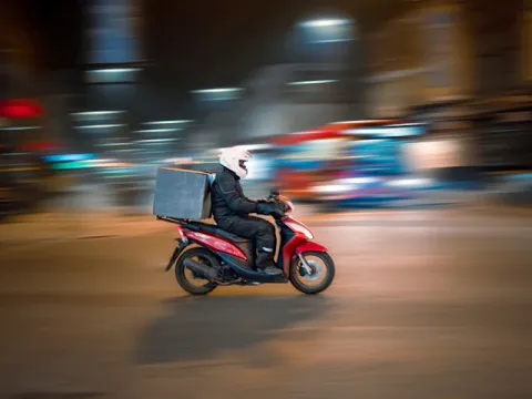 Entregador de moto com bolsa de entrega à noite